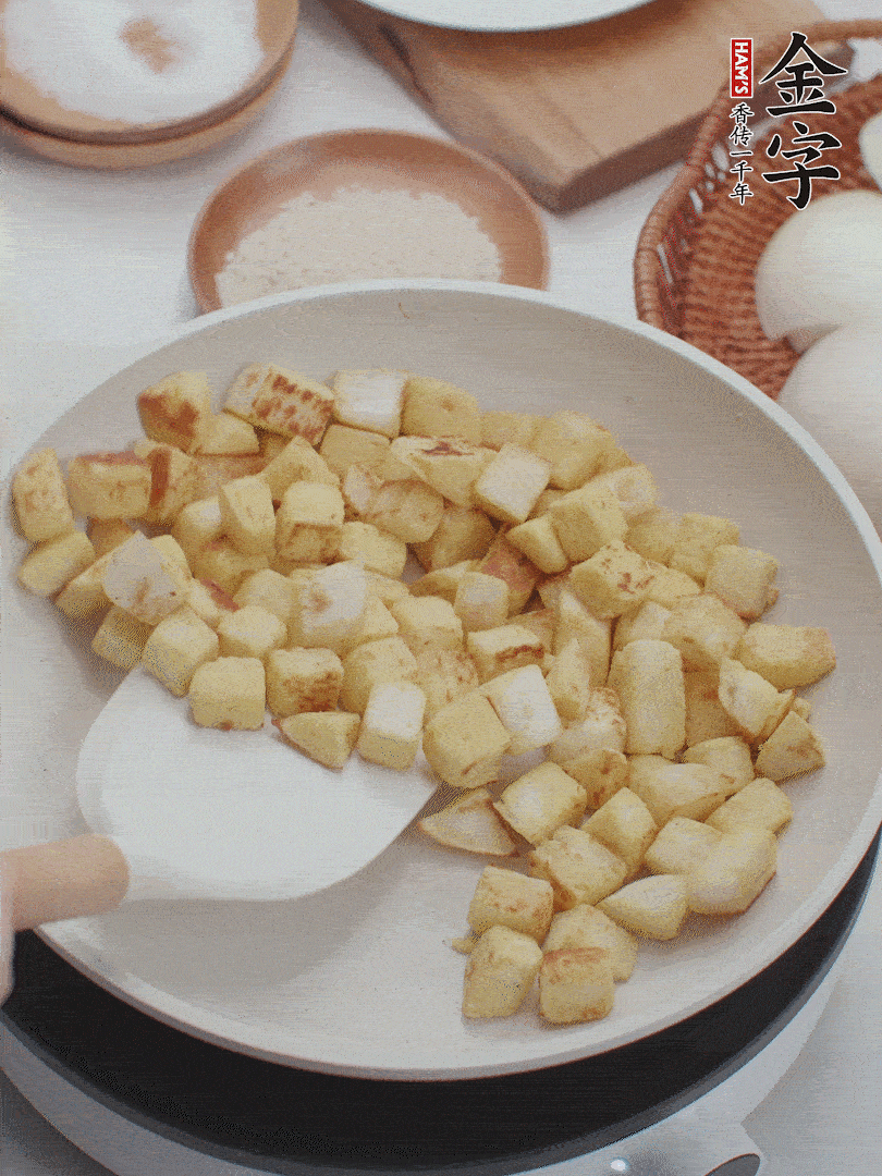 起鍋熱油，倒入饅頭丁，小火煎至蛋液凝固定型再翻面，饅頭丁部煎至金黃時(shí)盛起待用。
